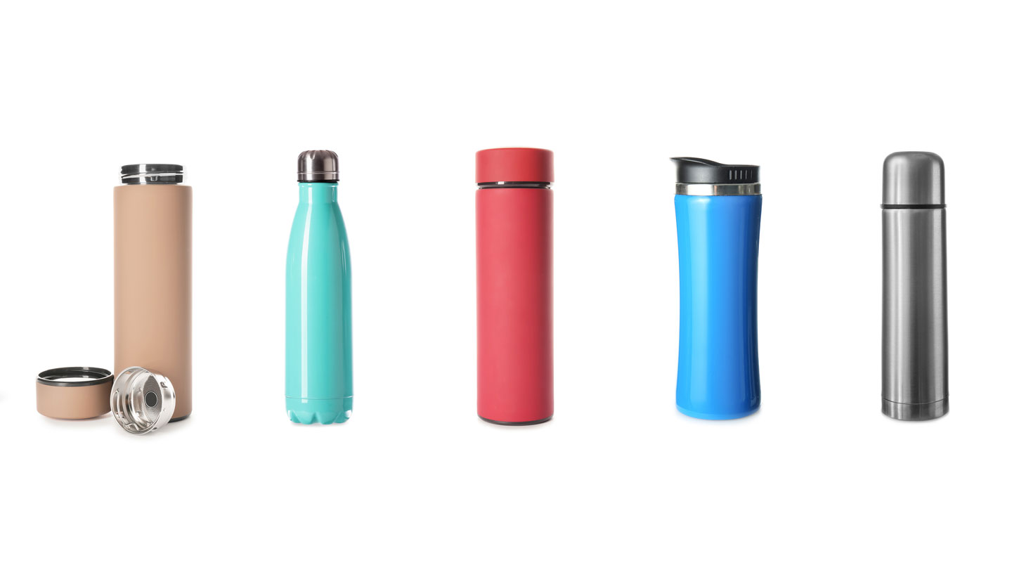 Gros plan sur les textures de trois gourdes en différents matériaux : acier inoxydable brossé, aluminium anodisé bleu et verre avec housse silicone, illustrant la diversité des finitions disponibles.